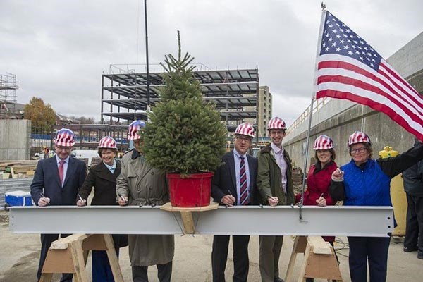 State Rep. Brian Dempsey, UMass Lowell Chancellor Jacqueline Moloney, Mayor James Fiorentini, Ron Trembly, Bill Grogan, Sally Cerasuolo-O'Rorke and Lisa Alberghini sign a beam during a topping off ceremony at Harbor Place. 